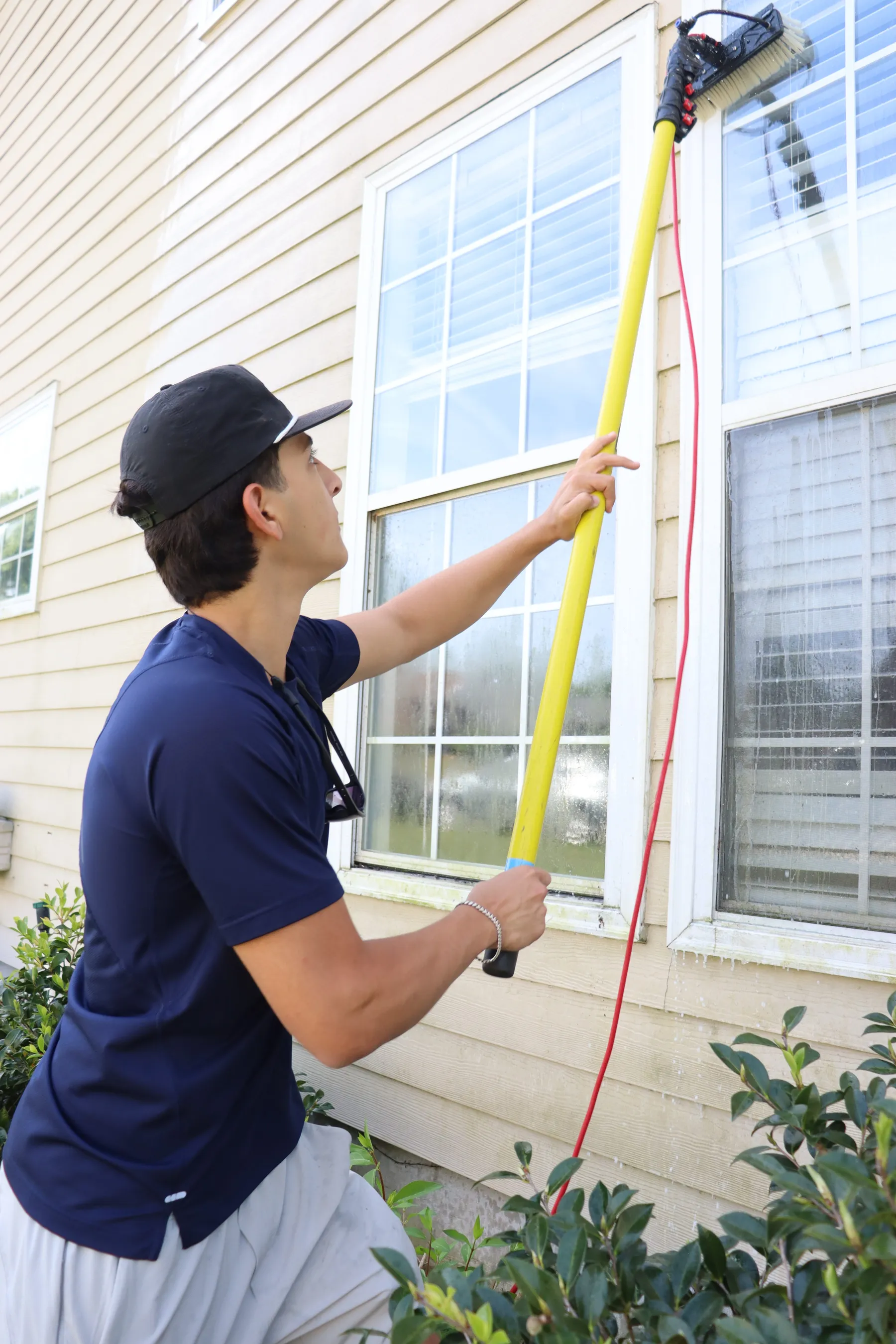 TEX Window Cleaning technician cleaning windows with a water-fed pole in Tallahassee